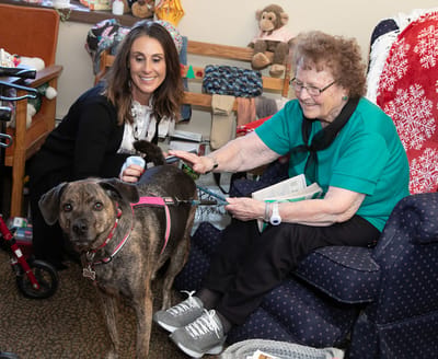 Staff and resident interacting with a therapy dog