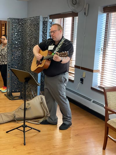 Staff member performing music for residents in a common area