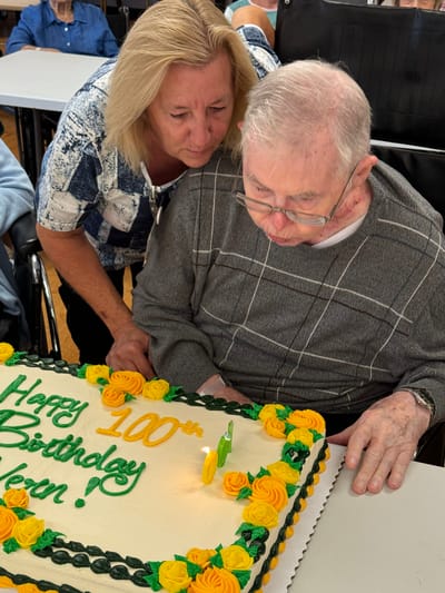 Residents celebrating a 100th birthday with a cake