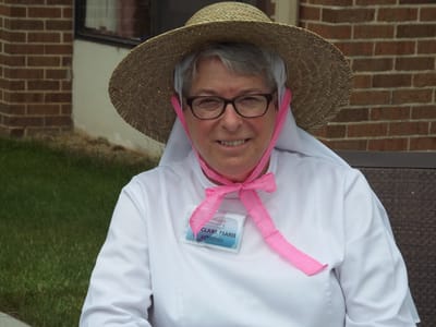Staff member in a hat and name badge outdoors