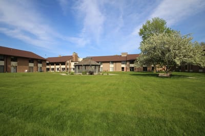Exterior view of St Monicas Senior Living campus with lawn and trees