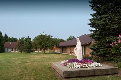 Outdoor view of a senior living facility with a statue and flowers