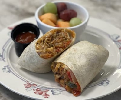 Close-up of a burrito with fruit and salsa on a plate