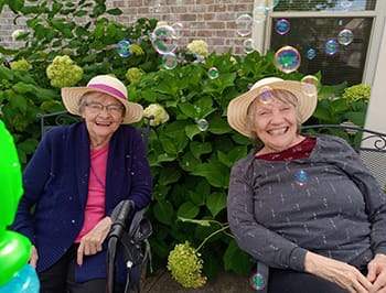Pro Health Care Regency Senior Comm Muskego, assisted living — Two smiling seniors wearing hats surrounded by bubbles