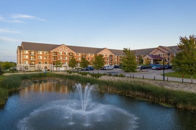 Exterior view of a senior living facility with pond and fountain