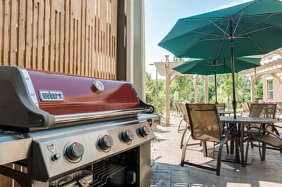 Outdoor grilling area with tables and umbrellas.
