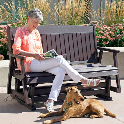 Resident sitting outdoors with a dog in a garden setting