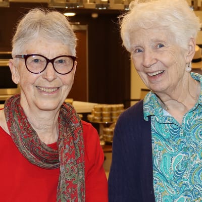 Two elderly women smiling together in a common area