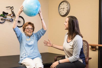 A resident playing with a blue ball during an activity