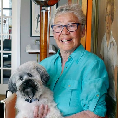 Resident holding a small dog in a warm interior setting