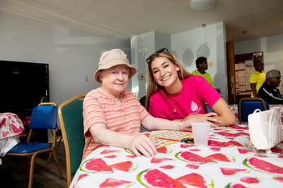 An elderly resident playing bingo with staff member
