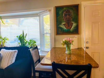 Dining area with a table, flowers, and a portrait on the wall