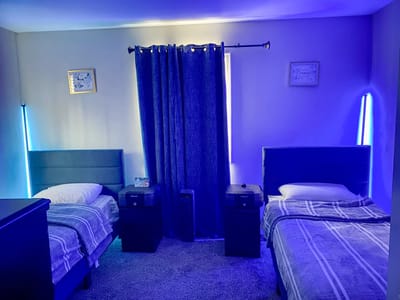 A cozy shared bedroom with two beds and blue lighting