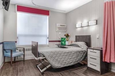 A private resident room with a bed and chair