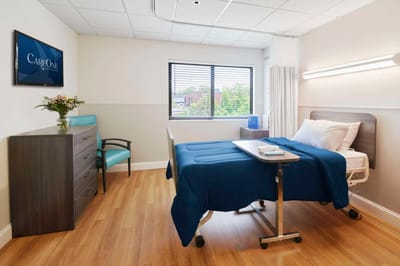 A neatly arranged resident room with a bed and chair