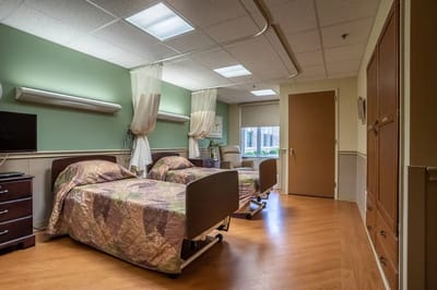A spacious resident room with two beds and natural light