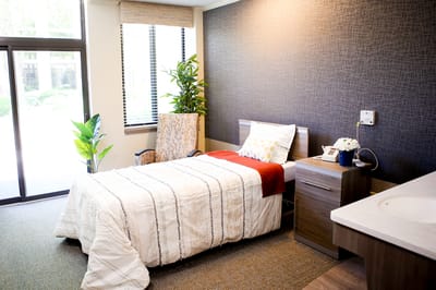 A cozy private room with a bed and armchair