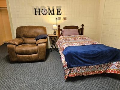 Cozy interior of a resident's room with a bed and chair