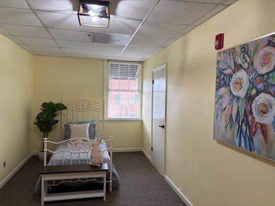 A bright private resident room with a bed and artwork