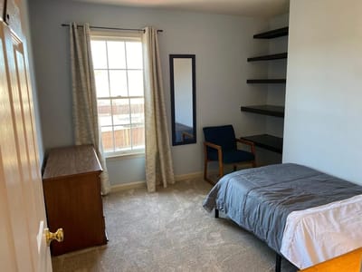 A simple private resident room with a bed and chair