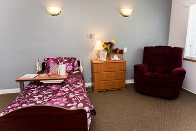 Cozy resident room with bed, chair, and flowers