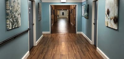 A well-lit hallway with artwork and wooden flooring