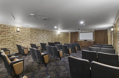 Empty theater room with rows of seats and a screen