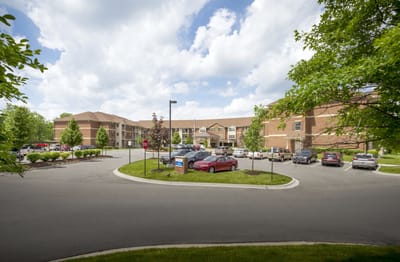 Exterior view of Pomeroy Living Rochester with parking lot and landscaping