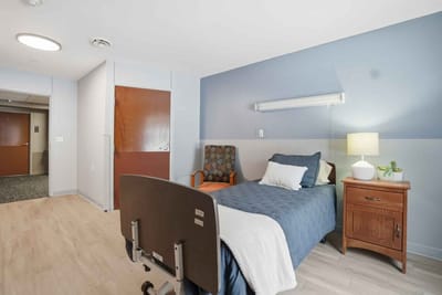A private resident room with a bed and chair