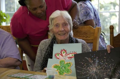 Resident engaged in art activity with staff support.