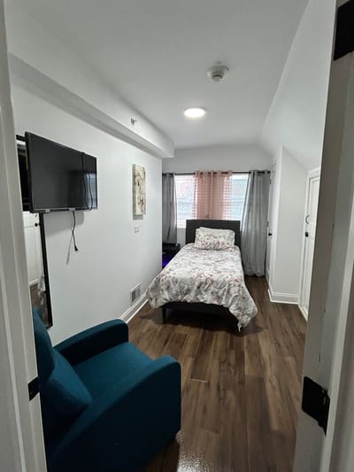 Bright private resident room with bed and chair