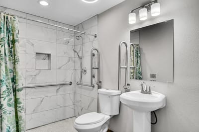 Accessible bathroom with safety features and floral shower curtain.