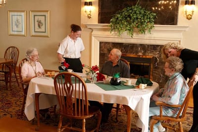 Residents enjoying a meal with staff in a dining room