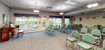 A common area with green chairs and a piano