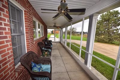 Covered porch area with chairs and ceiling fans