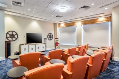A cozy theater room with orange chairs and a TV