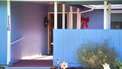 Front entrance of a senior living facility with a blue facade