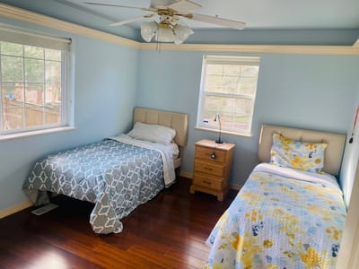Bright twin bedroom with two beds and wooden flooring.