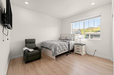 A cozy resident room with bed and chair