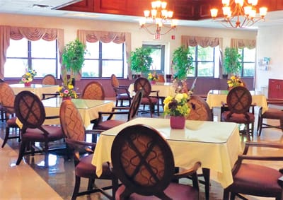 Dining area with tables and chairs decorated with flowers.