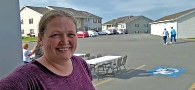 Outdoor view of the facility with a smiling staff member