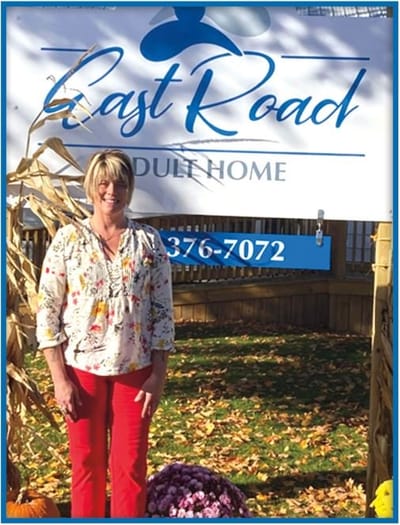 A resident standing in front of the facility sign outdoors