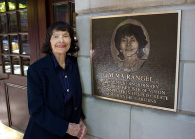 Woman standing beside a plaque honoring Alma Rangel