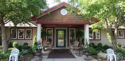 Front entrance of Heritage Manor with seating and flowers