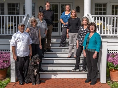 Staff members and a dog on the steps outside the facility