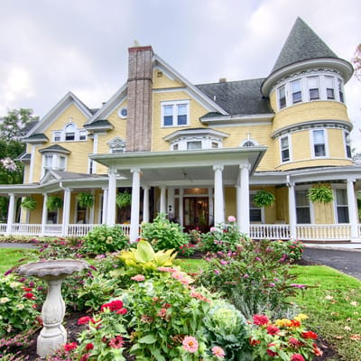 Exterior view of a large, historic nursing home building with gardens