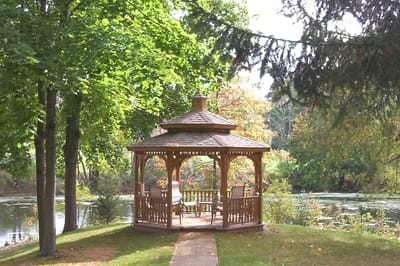 Outdoor gazebo by a pond surrounded by trees