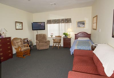 A well-furnished private resident room with a bed and seating area