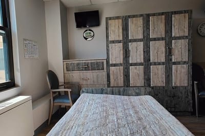 A private resident room with furniture and a TV