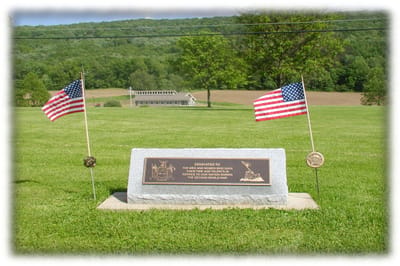 Memorial marker with flags in a grassy area